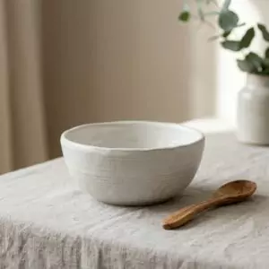 Bol Farine, en blancs cassés, collection Craie, posé sur une table en bois.
