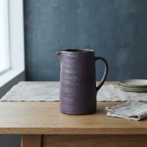 Pichet Améthyste, en violet, collection Ardoise, posé sur une table en bois.